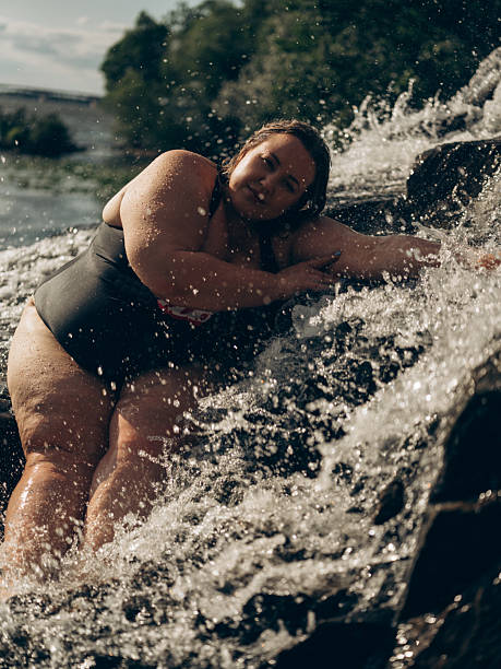 istock Confident Plus-Size Woman Relaxing by a Waterfall in Summer Nature 2230123519