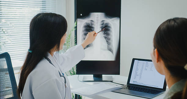 istock Young Asian female doctor analyzing lung X-ray and explaining diagnosis to patient during consultation in modern medical clinic office. 2230128482