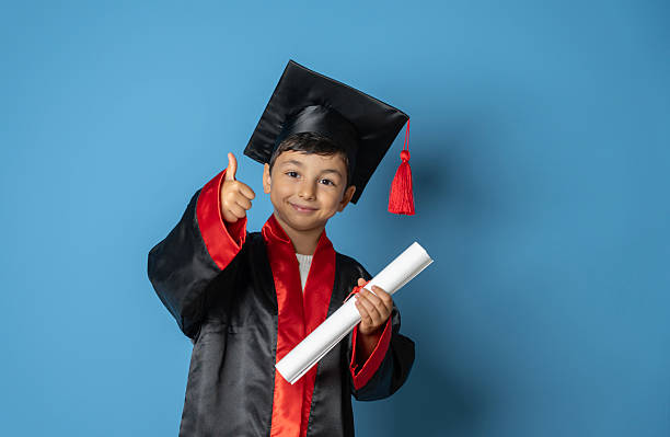 Cute Kid in Graduation Cap Posing with Joy and Confidence Making Thumbs Up