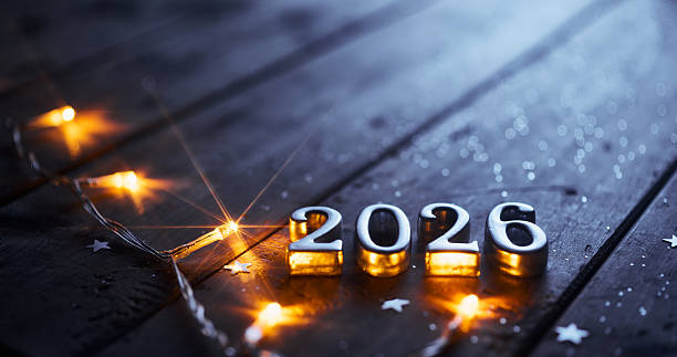 Shiny Silver 2026 Surrounded by Warm String Lights on Dark Wooden Background