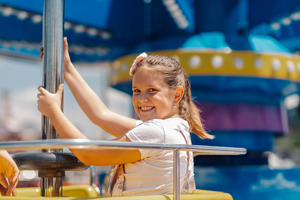 istock Smiling girl having fun on a carousel ride at amusement park 2230130777