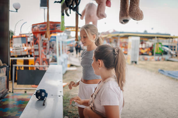 istock Two girls playing a ball rolling game at the funfair 2230130921