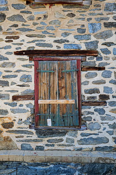 istock Very old stone building with shut wooden window blinds or shutter 2230132007