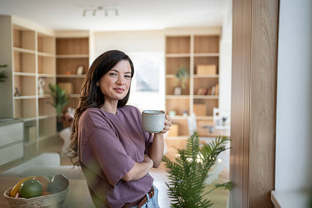 istock Smiling woman drinking coffee in modern apartment 2230133912