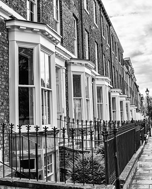 York, UK. August 7, 2025. A view down a street of town houses with bay windows. There are railings in the foreground and sky with cloud above.