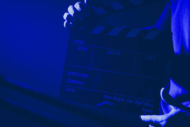 Film Crew Member Holding a Clapperboard in Dimly Lit Studio Environment