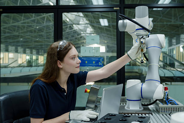 istock female robotics trainee adjusting robotic arm in smart factory using laptop and manual control system during training session focusing on workflow accuracy and hands-on skill learning 2230136491