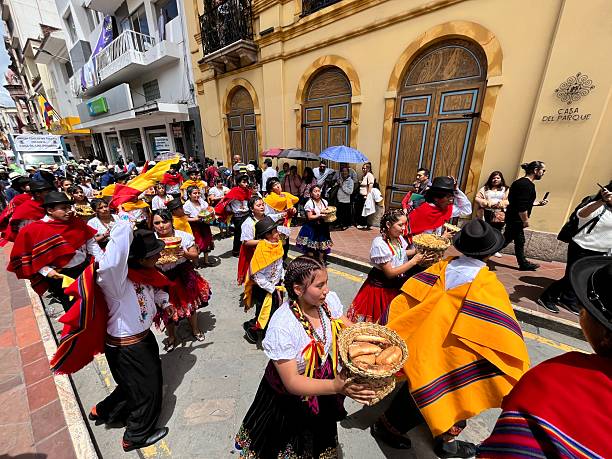 Cuenca, Azuay, Ecuador - April 10, 2025: People wearing traditional costumes are parading along Simón Bolívar street in Cuenca, Ecuador, carrying baskets of bread during a cultural celebration