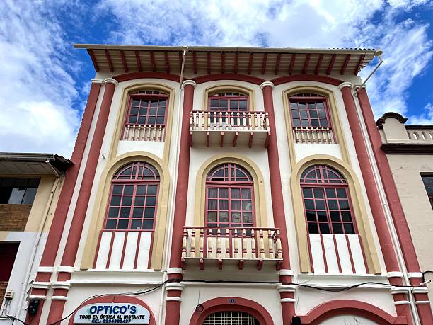 Cuenca, Azuay, Ecuador - April 13, 2025: Low angle view of a traditional building showcasing the colonial architecture of Cuenca, Ecuador, with its vibrant colors and intricate details standing against a bright blue sky