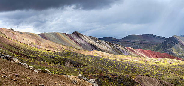 Palccoyo, Peru, November 14, 2021: Panoramic view of multi colored mountains in the locality of Palccoyo in Peruvian Andes under cloudy sky.