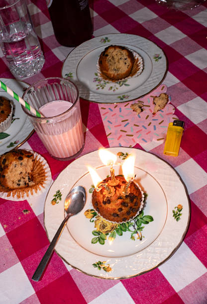 Candid shot with movement of birthday celebration with cupcakes and milkshake on tablecloth. Flash.