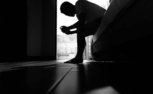 The depression man use phone and sit on bed in the morning