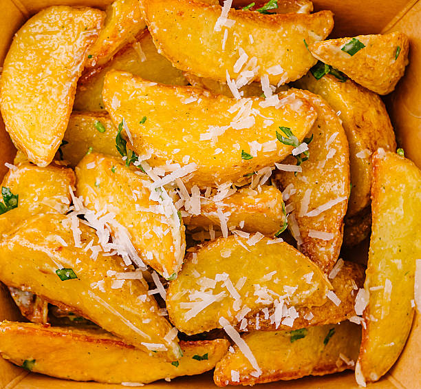 Crispy potato wedges topped with fresh herbs and cheese in a takeout box