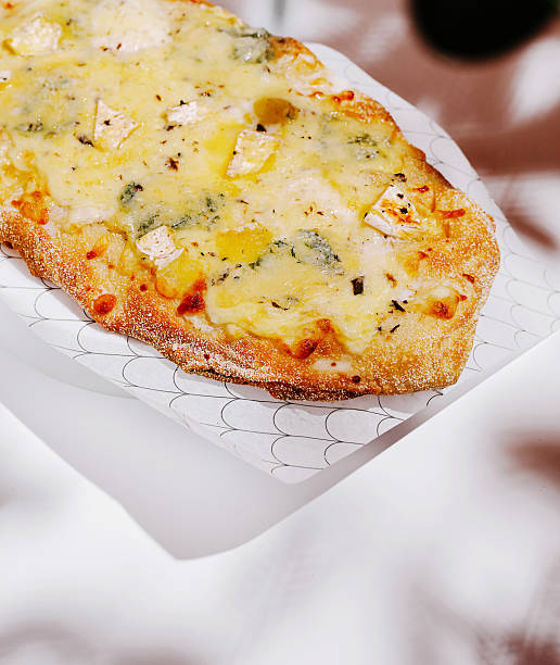 Cheesy flatbread topped with herbs and olives served at a cozy eatery