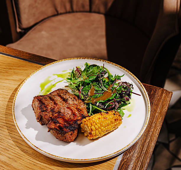 istock Delicious grilled steak with corn and fresh salad served at a modern restaurant 2230142114