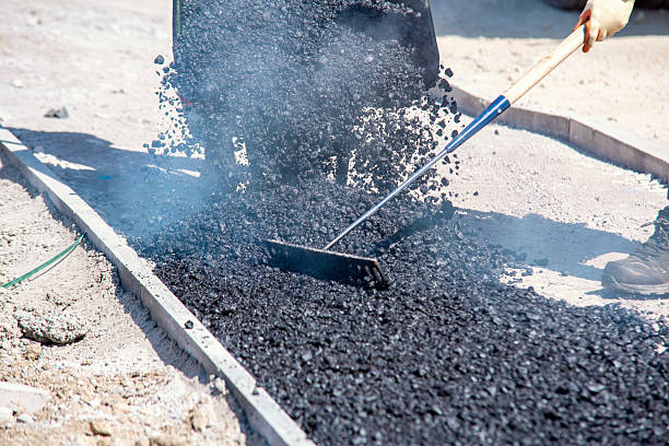 istock Construction workers in high-visibility gear are applyin gfresh hot asphalt to roadway surface 2230145343