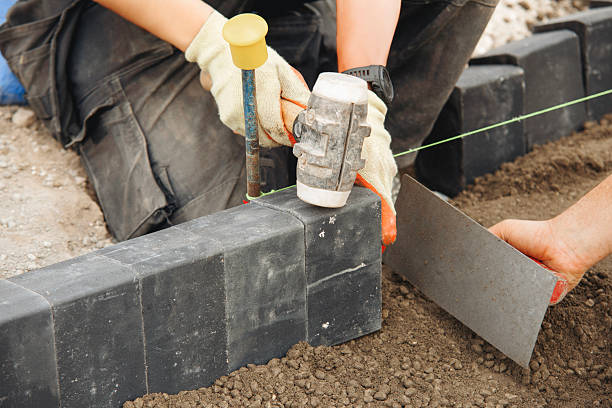 istock Close-up of builder  carefully placing black bricks on  prepared base at construction site 2230145752