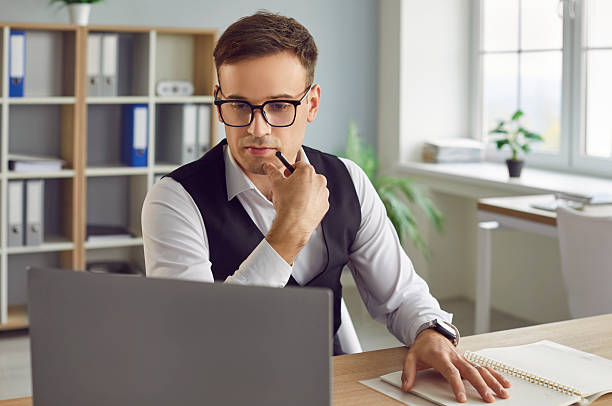 istock Businessman working in office at desk, watching laptop, thinking, considering 2230146523