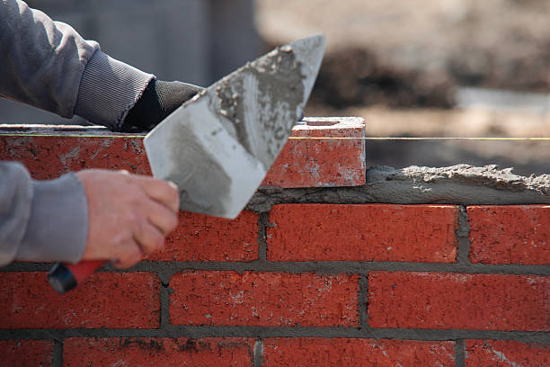 istock Close-up of skilled bricklayer working on construction site laying bricks for wall construction 2230147175