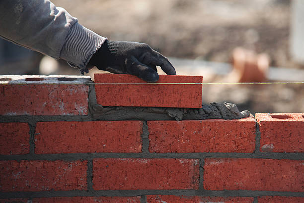 istock Close-up of skilled bricklayer working on construction site laying bricks for wall construction 2230147867