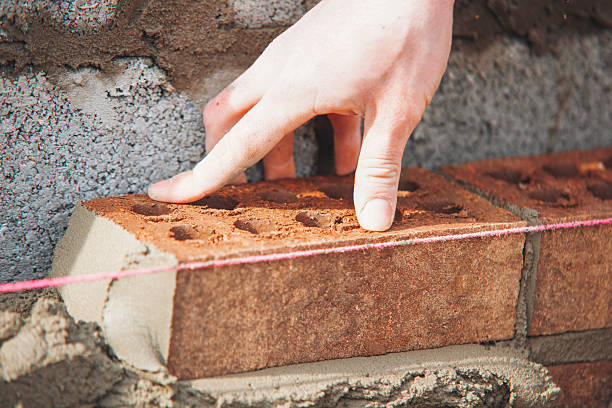 istock Close-up of skilled bricklayer working on construction site laying bricks for wall construction 2230149468