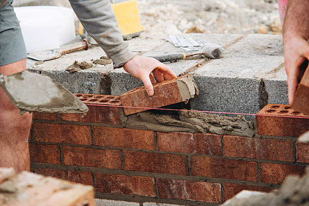 istock Close-up of Skilled bricklayer laying bricks with trowel on construction site 2230149896