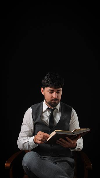 istock Man in Formal Attire Reading a Book with Concentration 2230150738