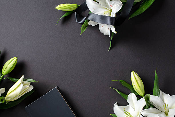 istock Elegant flat lay composition for funeral, mourning, condolence. Top view white lily flowers, Bible, black ribbon on dark background,. 2230156065