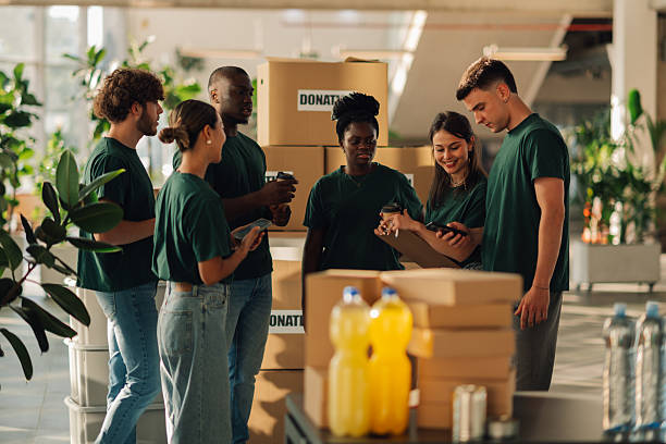 istock Volunteers using mobile phones and organizing donations in cardboard boxes 2230159334