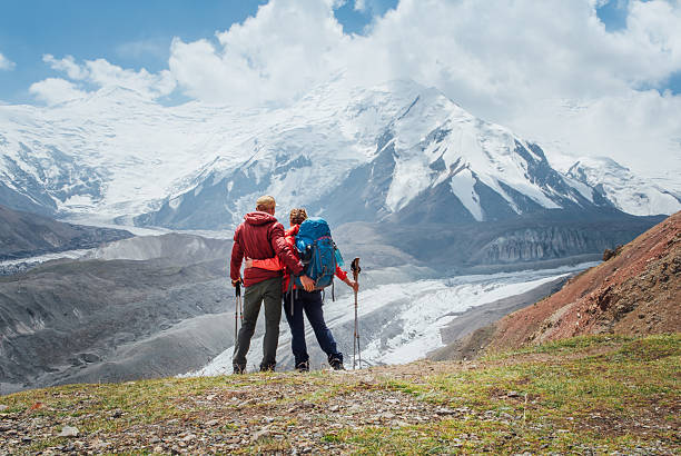 istock Backpackers couple with backpacks hugging enjoying Pamir mountains during Lenin peak ascent with mountain peaks in background. Extreme active people, high-altitude Pamir area mountaineering concep 2230175830
