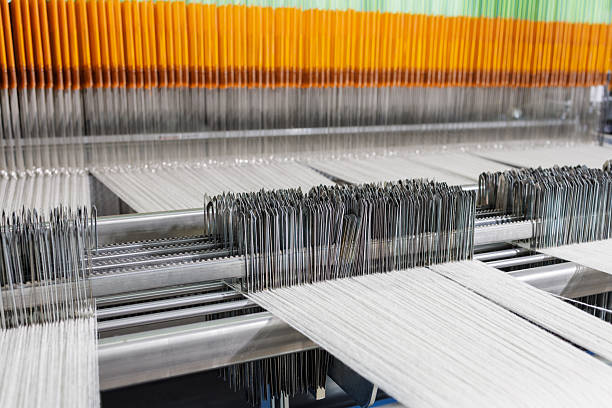 Detailed view of an industrial weaving loom showing warp, heddles and reed for textile production, automation and engineering visuals.