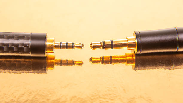 Two different metal screwable analog audio stereo adapters with socket mini-Jack and plug Jack on the edges of golden color on a gray background
