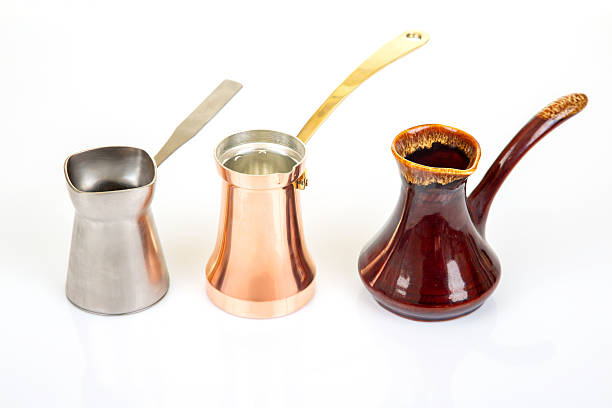 istock Collection of Turkish coffee makers in metallic silver, glossy red ceramic, and shiny copper with gold handles, displayed on a white surface, great for coffee lover and cultural heritage visuals 2230176654