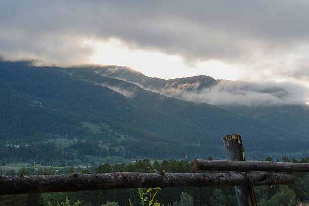 Scenic view of Canadian Rocky Mountains at sunrise, with log railing in foreground