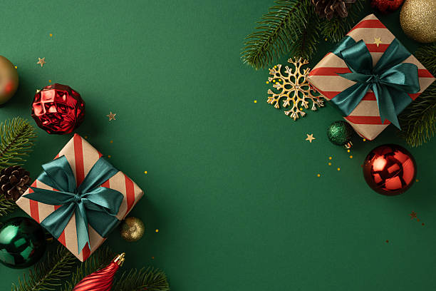 istock Holiday-themed flat lay featuring decorated gift boxes, ornaments, pine branches, and festive accents on a green background 2230179507