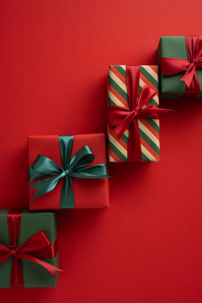 istock Colorfully wrapped holiday presents with ribbons arranged on a vertical bright red background 2230179535