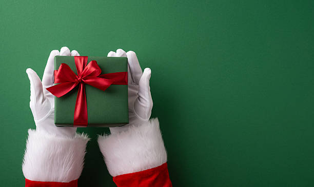 istock Santa's hands holding a green gift tied with a red bow on a holiday backdrop 2230179537