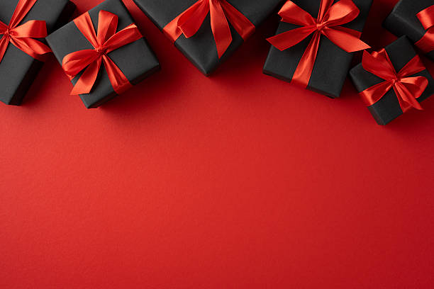 istock Various black gift boxes with red ribbons on a red background, conveying celebration 2230179540