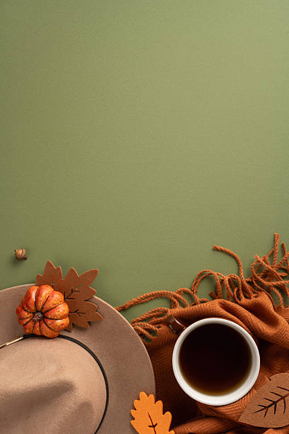 istock Flat lay vertical composition featuring fall-inspired items like a cup, scarf, hat, pumpkins, and leaves on a green backdrop, evoking the warm and cozy feelings of the autumn season 2230179552
