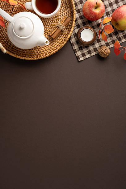 istock Tea vertical setup featuring a teapot, apples, and cinnamon on a woven tray with autumn decorations 2230179564
