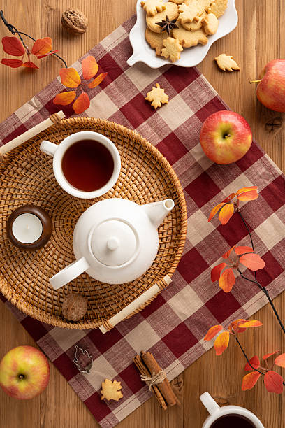 istock Warm vertical scene featuring a teapot, apples, cookies, and leaves arranged on a rustic table 2230179567