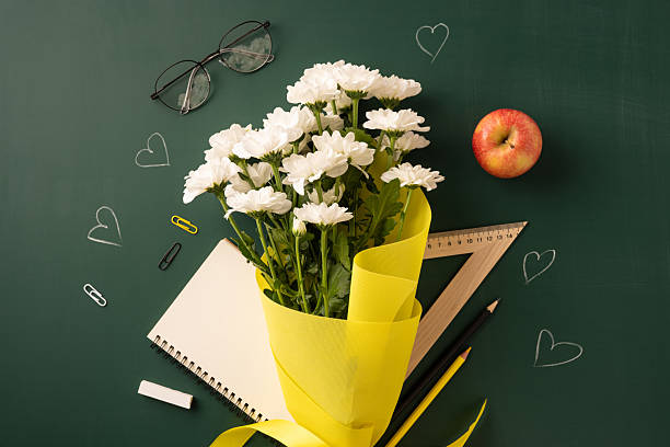 istock White daisies in yellow wrapping with schoolbook, apple, and ruler setup for teachers day 2230179573