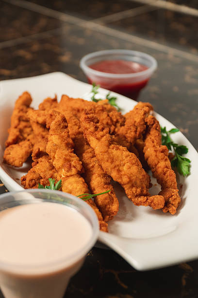 istock A close-up of fried chicken strips on a plate with sauces. 2230199215