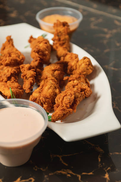 istock A close-up view of fried chicken strips with sauces. 2230199225
