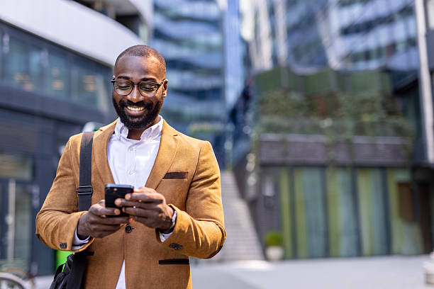 istock Smiling man texting outdoors in modern urban environment 2230204697