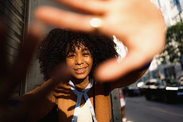 istock Young woman framing her face with hands, playing with sunlight 2230205108