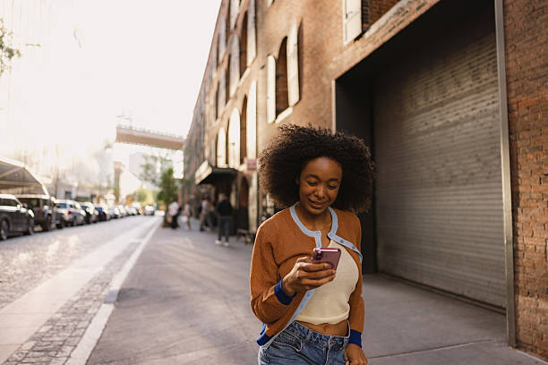 istock Young woman using phone while walking in New York City 2230205119