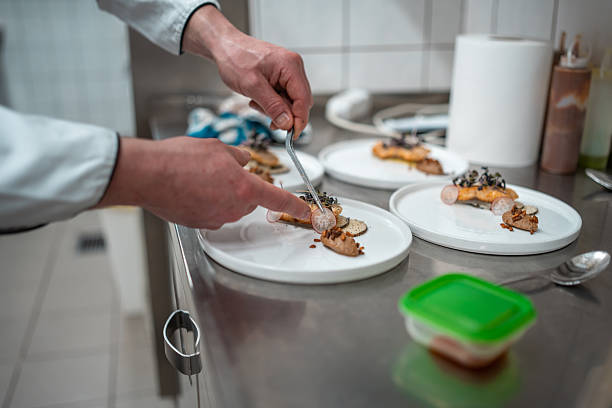 istock Professional Chef Hands Plating Gourmet Dish On White Ceramic Plates In Restaurant Kitchen 2230205518