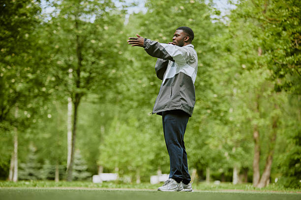 istock Young Adult Black Man Stretching Arms Outdoors in Green Park Setting 2230207702