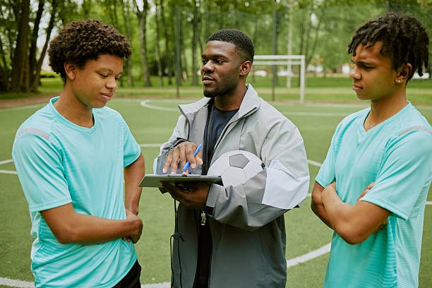 istock Black Coach Instructing Two Teenager Boys during Soccer Training Session 2230207917